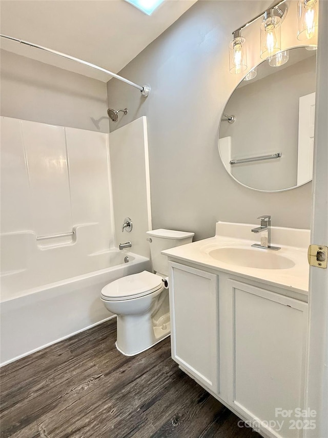full bathroom with wood finished floors, toilet, vanity, and shower / washtub combination