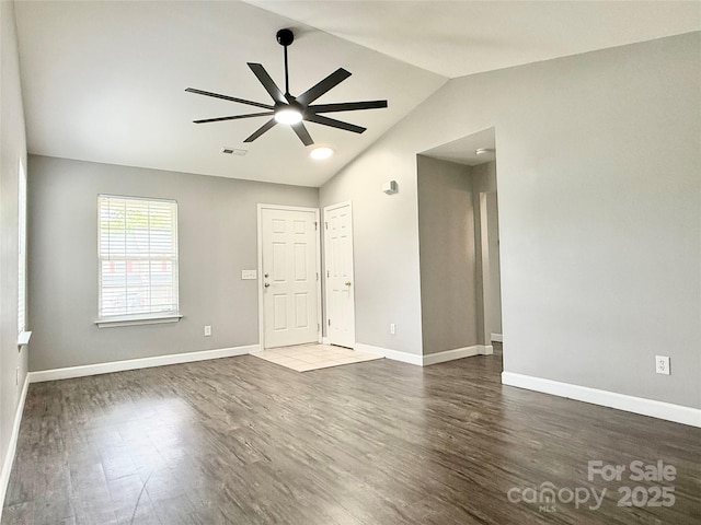 empty room with a ceiling fan, wood finished floors, lofted ceiling, and baseboards