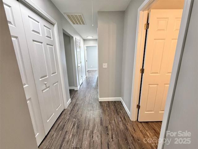 hallway featuring dark wood-type flooring and baseboards