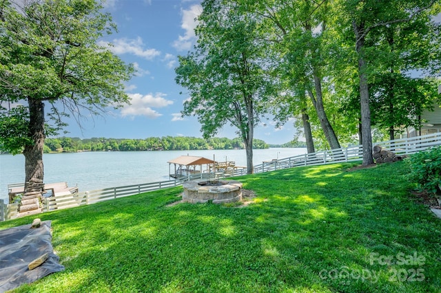 dock area featuring a yard, a water view, fence, and a fire pit