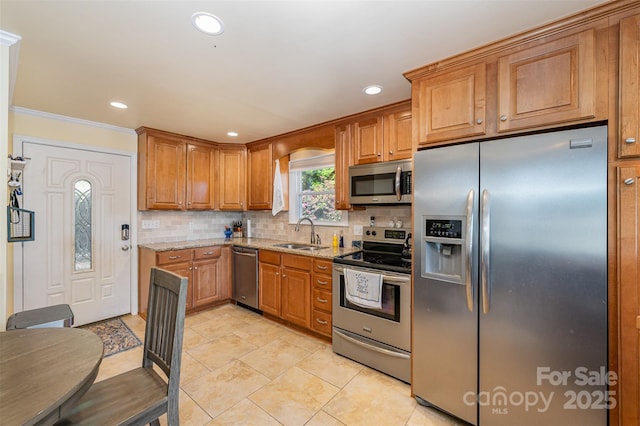 kitchen featuring backsplash, appliances with stainless steel finishes, light stone countertops, brown cabinets, and a sink