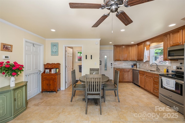 kitchen with a sink, appliances with stainless steel finishes, crown molding, and ceiling fan