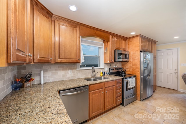 kitchen featuring decorative backsplash, brown cabinetry, appliances with stainless steel finishes, a sink, and light stone counters