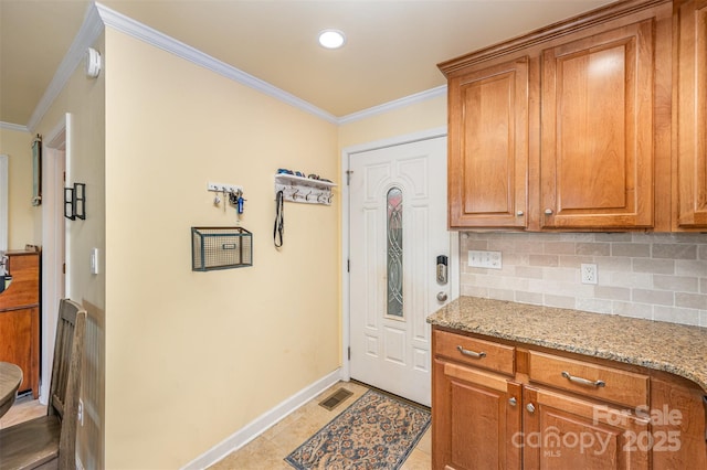 kitchen with crown molding, baseboards, tasteful backsplash, and brown cabinetry