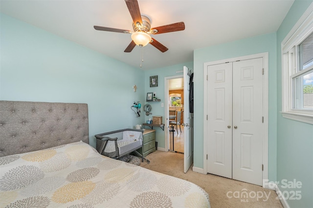 bedroom featuring light colored carpet, a ceiling fan, baseboards, and a closet