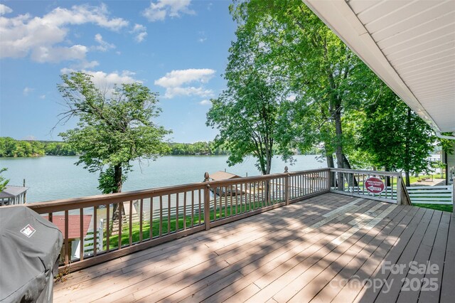 wooden terrace featuring a water view and a grill