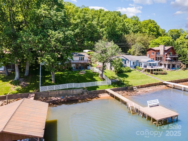 view of dock with a lawn, a water view, stairway, and fence