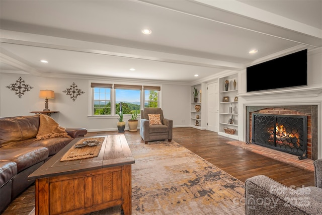 living room featuring built in features, baseboards, a lit fireplace, recessed lighting, and dark wood finished floors