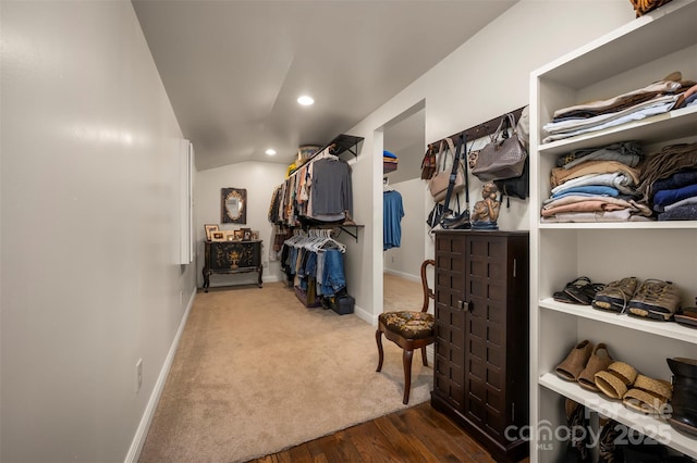 walk in closet featuring carpet, wood finished floors, and lofted ceiling