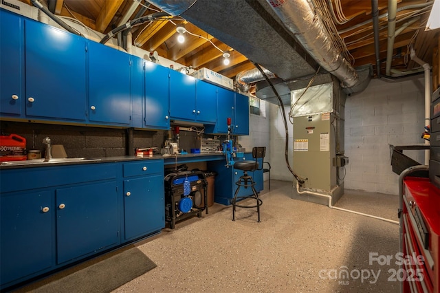 unfinished below grade area with concrete block wall, heating unit, and a sink