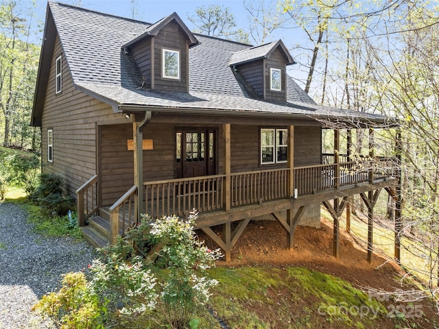 chalet / cabin featuring roof with shingles and covered porch