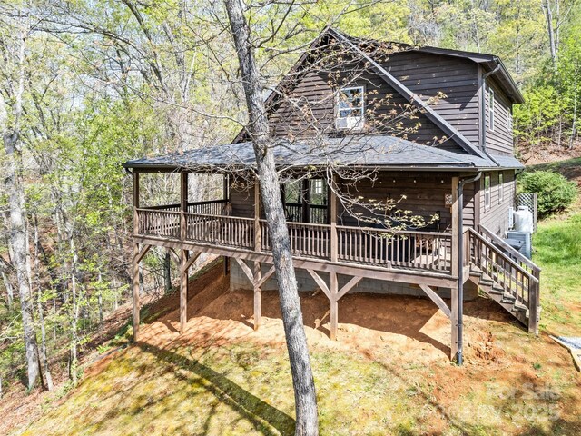 exterior space with stairway, a forest view, and a wooden deck