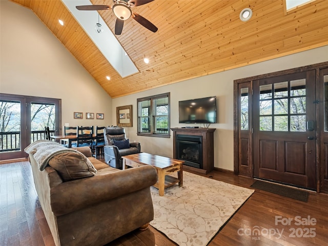 living area featuring high vaulted ceiling, wood ceiling, a ceiling fan, dark wood finished floors, and a skylight