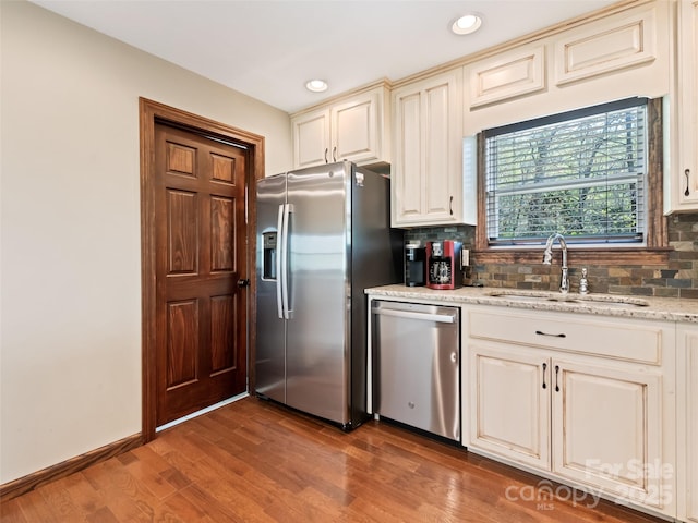 kitchen featuring a sink, stainless steel appliances, recessed lighting, decorative backsplash, and wood finished floors