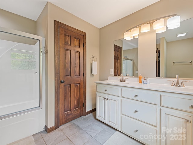 full bath featuring double vanity, a sink, baseboards, and tile patterned flooring