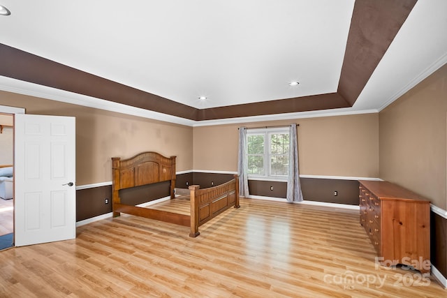 unfurnished bedroom with baseboards, ornamental molding, a raised ceiling, and wood finished floors