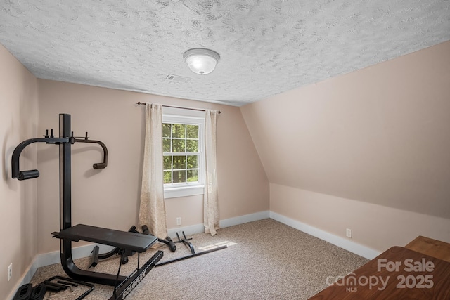 exercise area featuring carpet flooring, a textured ceiling, and baseboards