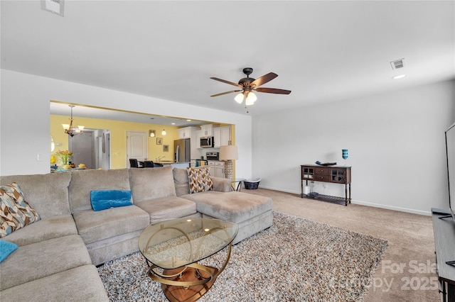 living area with baseboards, ceiling fan with notable chandelier, light colored carpet, and visible vents
