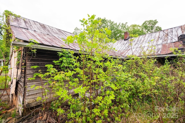 view of side of home featuring a chimney and metal roof
