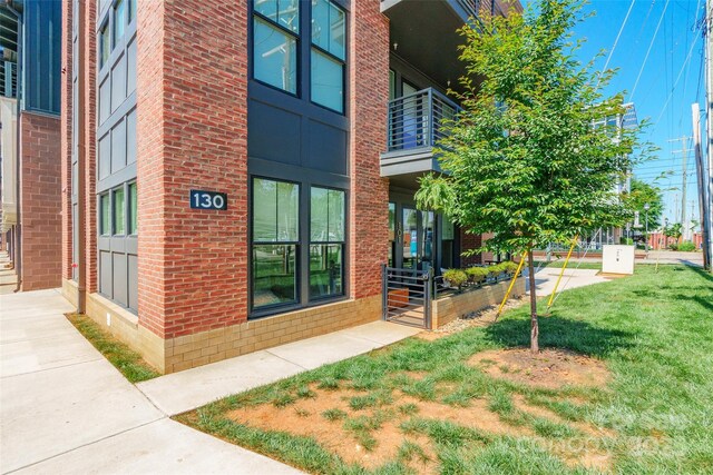 view of exterior entry with a yard and brick siding