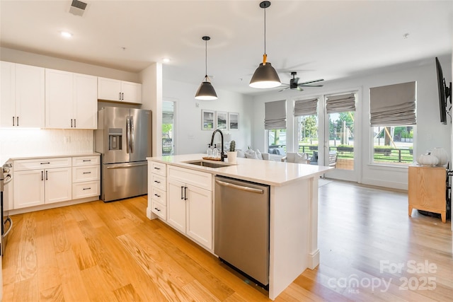 kitchen with a sink, appliances with stainless steel finishes, light wood finished floors, and visible vents