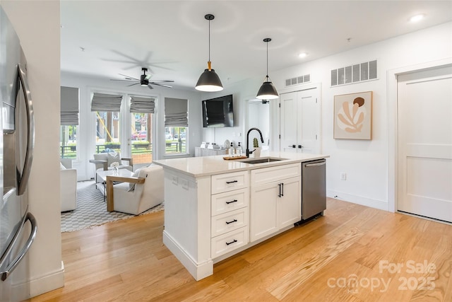 kitchen featuring visible vents, a sink, light wood-style floors, and stainless steel appliances