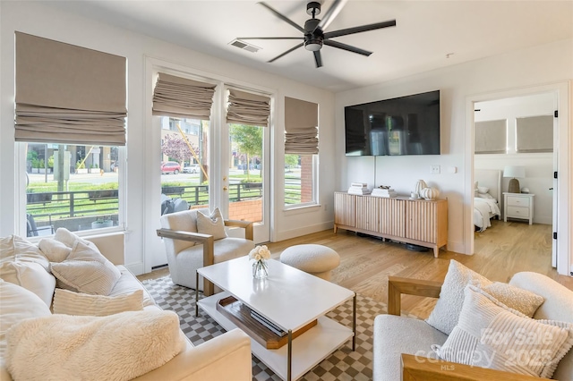 living room featuring a ceiling fan, baseboards, visible vents, and light wood-style floors
