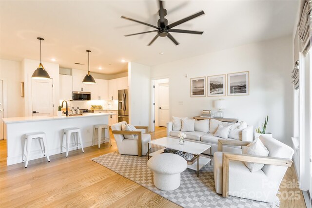 living room with recessed lighting, a ceiling fan, and light wood finished floors