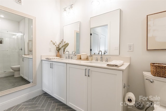 full bath with double vanity, a sink, a stall shower, and toilet