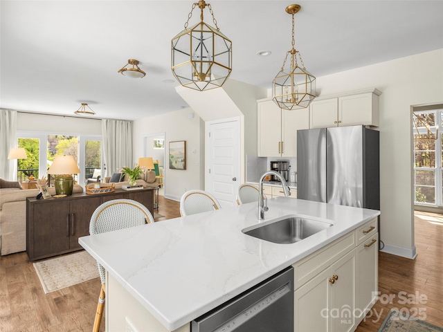 kitchen featuring open floor plan, appliances with stainless steel finishes, a healthy amount of sunlight, and a sink