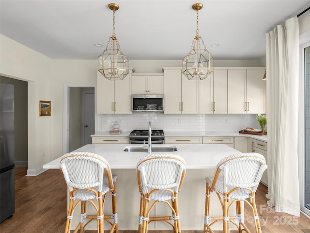 kitchen with backsplash, pendant lighting, a sink, light countertops, and stainless steel appliances