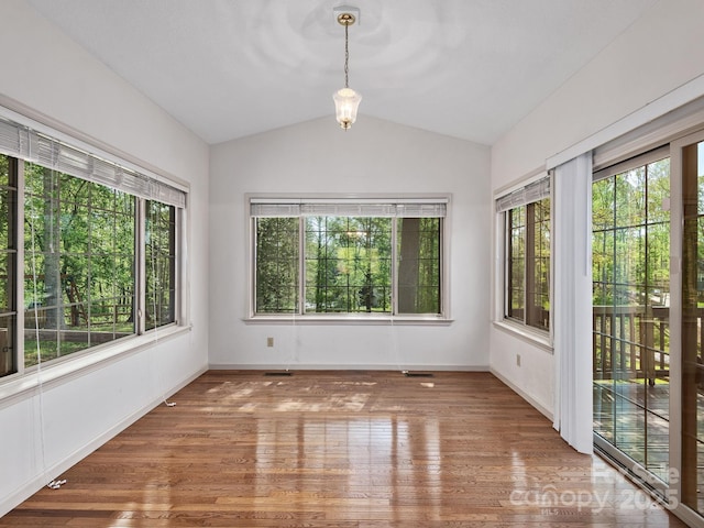 empty room with visible vents, baseboards, wood finished floors, and vaulted ceiling
