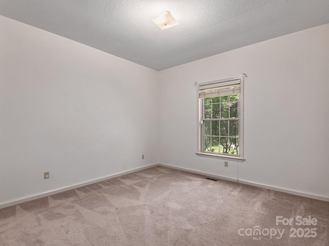 carpeted spare room featuring a textured ceiling, baseboards, and visible vents