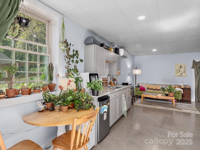 kitchen featuring concrete flooring, light stone counters, a sink, refrigerator, and a wall mounted AC