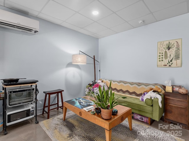 living area featuring an AC wall unit, concrete flooring, and a drop ceiling