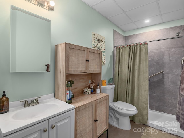 full bathroom with vanity, a drop ceiling, a stall shower, and toilet