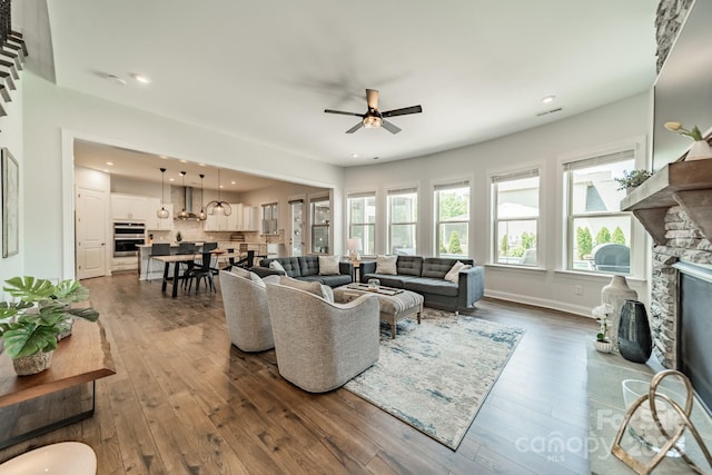 1107 Castle Rd, Indian Land, SC 29707 - living area with a ceiling fan, a stone fireplace, dark wood-style flooring, recessed lighting, and baseboards