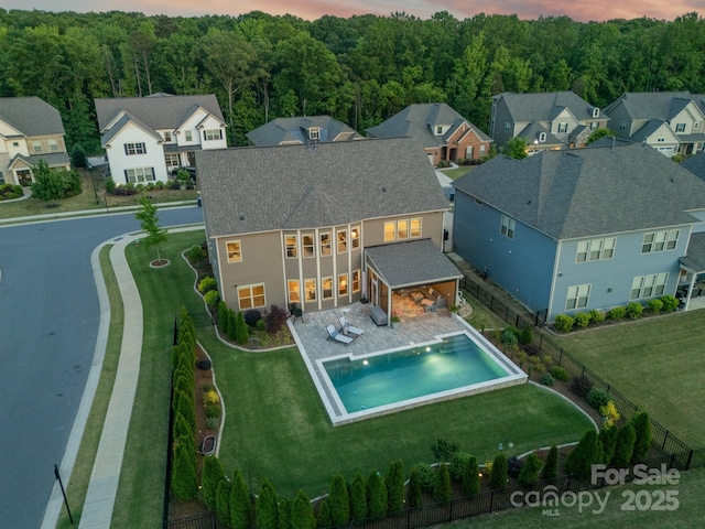 1107 Castle Rd, Indian Land, SC 29707 - back of house at dusk with roof with shingles, a patio, a fenced backyard, a fenced in pool, and a lawn