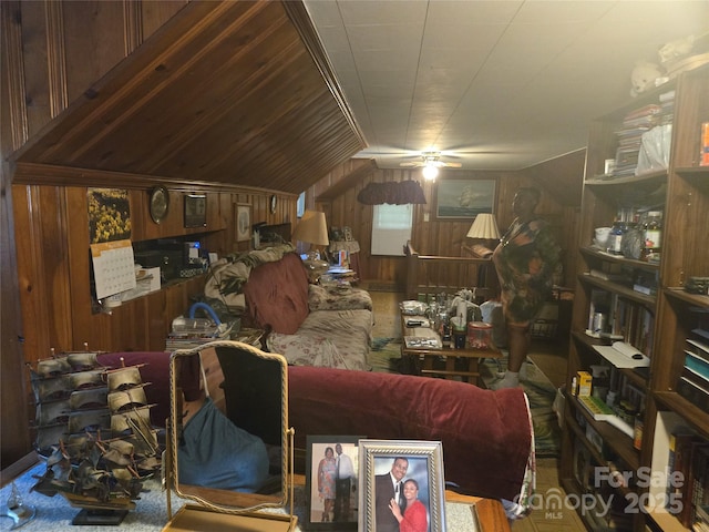 living area with wood walls, a ceiling fan, and lofted ceiling