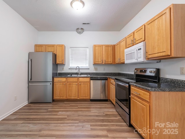 6212 Derryfield Dr, Charlotte, NC 28213 - kitchen with appliances with stainless steel finishes, light wood finished floors, a textured ceiling, and dark stone counters
