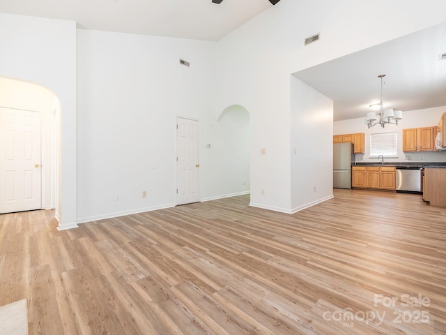 6212 Derryfield Dr, Charlotte, NC 28213 - unfurnished living room featuring high vaulted ceiling, arched walkways, a chandelier, and light wood-style flooring