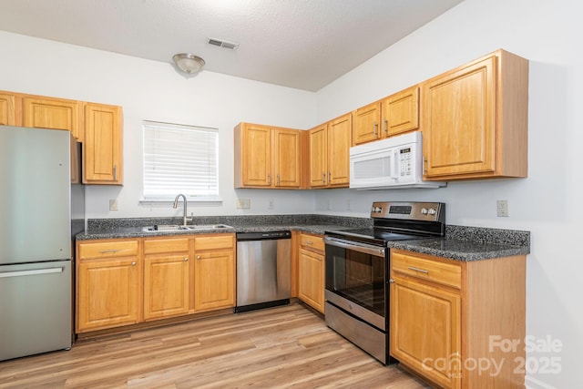 6212 Derryfield Dr, Charlotte, NC 28213 - kitchen with appliances with stainless steel finishes, light wood finished floors, a textured ceiling, and dark stone counters