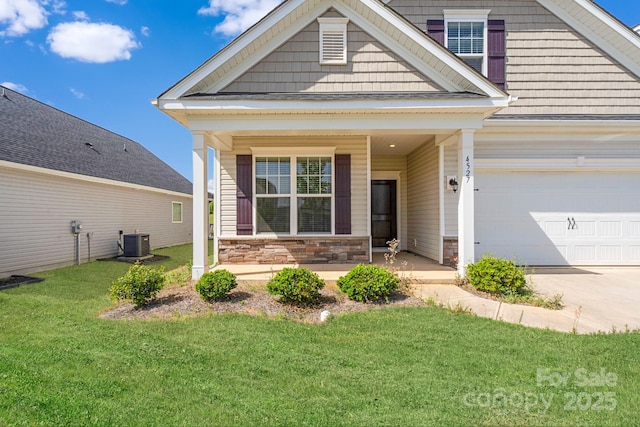 view of front of home featuring stone siding, a porch, a front yard, cooling unit, and driveway