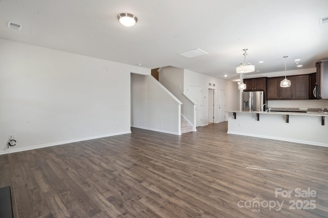 unfurnished living room with visible vents, dark wood finished floors, and baseboards