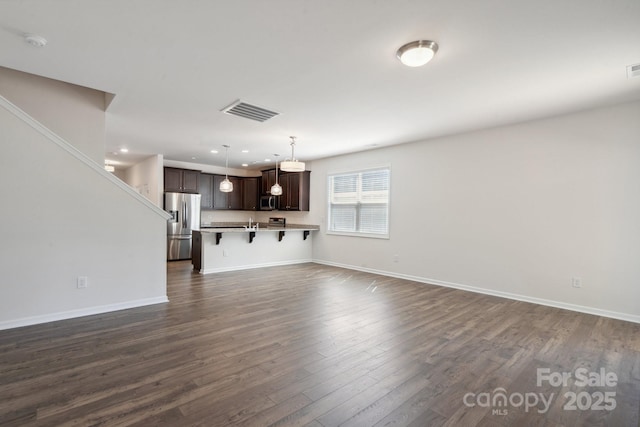 unfurnished living room featuring recessed lighting, baseboards, visible vents, and dark wood finished floors