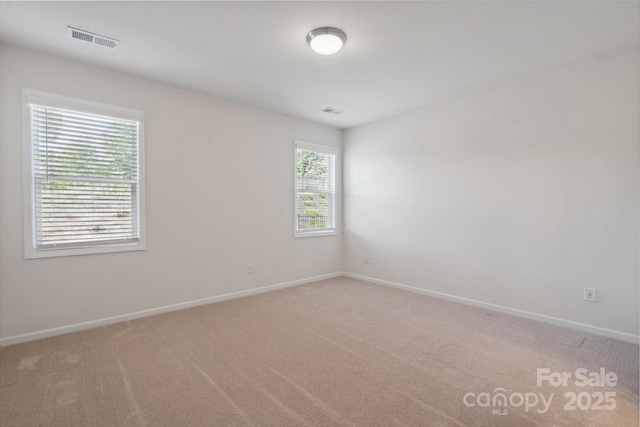 unfurnished room featuring baseboards, light carpet, and visible vents