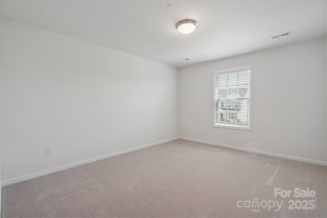 spare room featuring baseboards, light carpet, and visible vents
