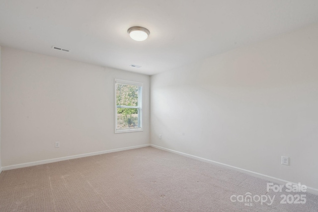 spare room featuring visible vents, baseboards, and light colored carpet