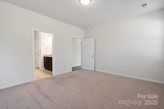 unfurnished bedroom featuring connected bathroom, baseboards, visible vents, and light carpet