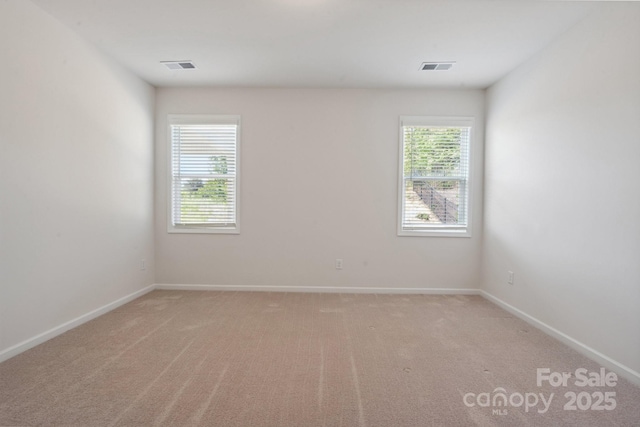 spare room featuring baseboards, visible vents, and light carpet